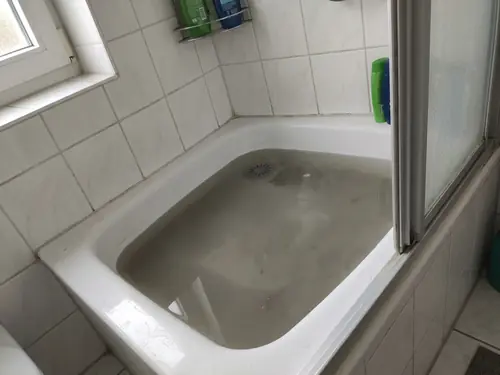 Duschwanne, in der trübes Wasser steht